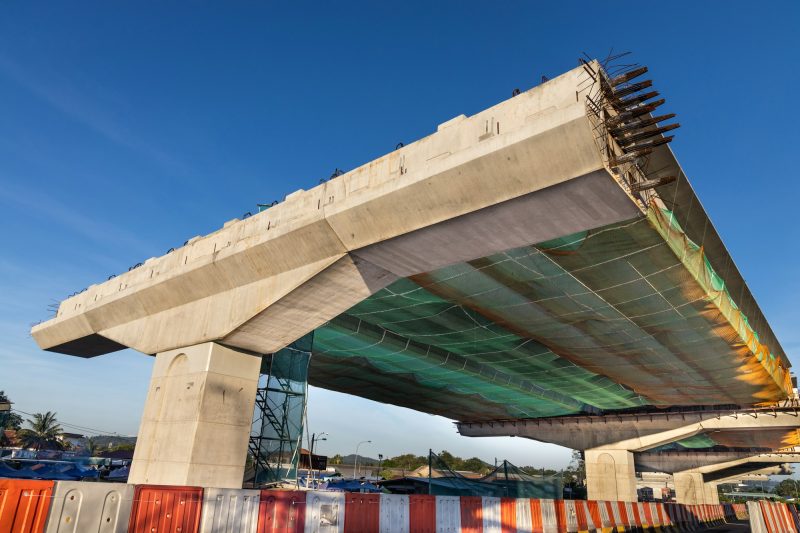 Construction of highway overpass bridge infrastructure in progress with morning sun rays